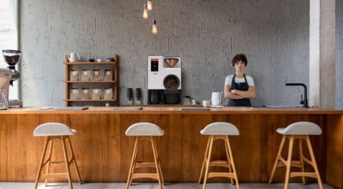 Barista behind coffee counter next to Bellwether electric roaster