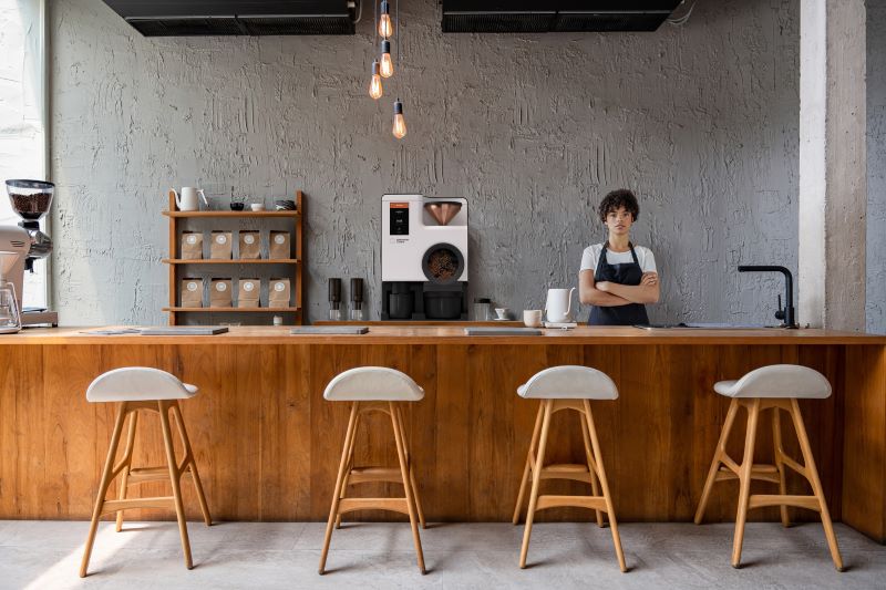 Barista behind coffee counter next to Bellwether electric roaster