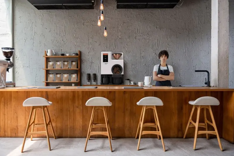 Barista behind coffee counter next to Bellwether electric roaster